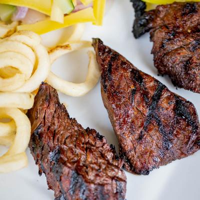 A close up of a plate with steak tips, fries, and salad.