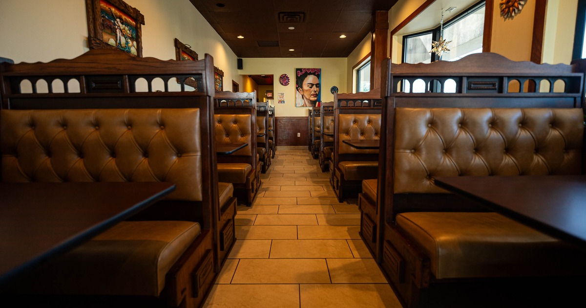 A cozy restaurant interior with brown leather booths lining both sides of a tiled aisle
