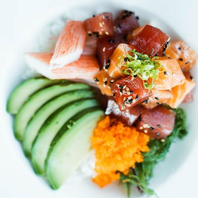 A dish with salmon and veggies atop a bed of rice.