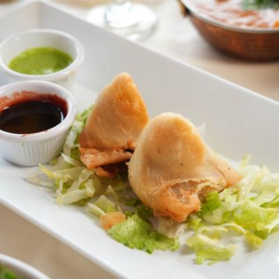 Samosa served on a bed of shreded lettuce with two dipping sauces.