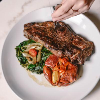 Grilled steak served with sauteed greens, roasted tomatoes and onions.