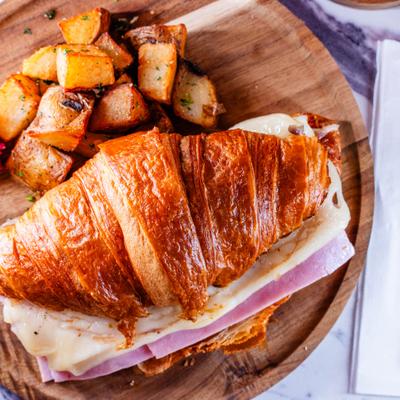 Ham and cheese croissant sandwich served with home fries.