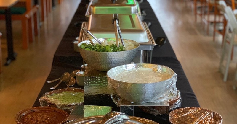 A long table with chafing dishes and food bowls on it