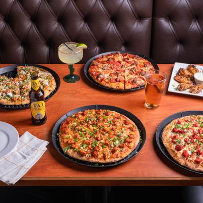 Variety of pizzas served on the table with drinks.