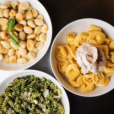 Potato gnocchi, cheese tortelloni, and pesto fusilli served in white bowls.