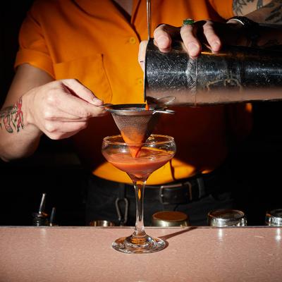 Bartender straining a cocktail.