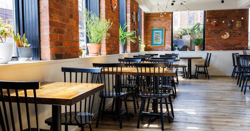 Interior, dining area, wooden top tables for two and four people, red brick walls