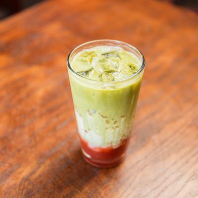 Glass of layered iced strawberry matcha latte.
