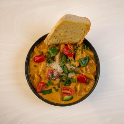 Chicken Masala Alfredo Pasta served with a slice of bread.