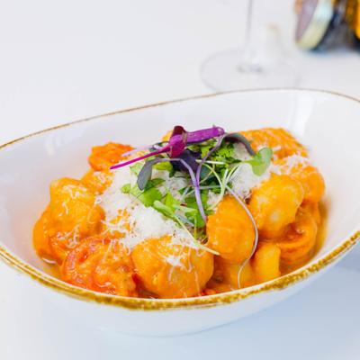 Gnocchi in a creamy tomato-based sauce, garnished with grated cheese and microgreens.