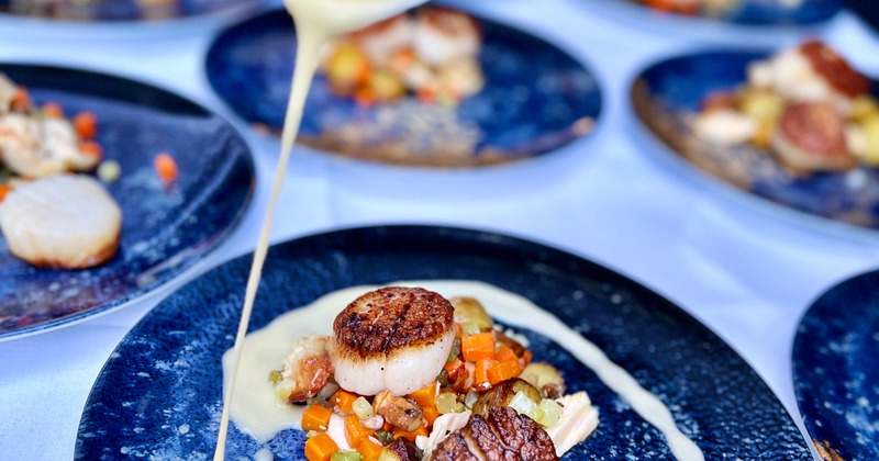 Dish being finished with a sauce on a plate