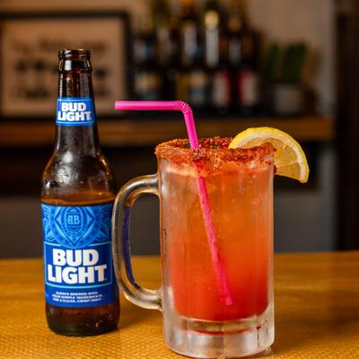 Michelada cocktail in a glass mug, served alongside a bottle of beer.