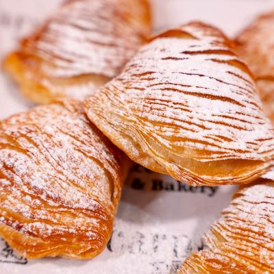 Shell shaped pastry with a sweet filling topped with powdered sugar, close up.