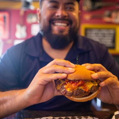 Smiling Male guest eating Western Bacon Cheeseburger