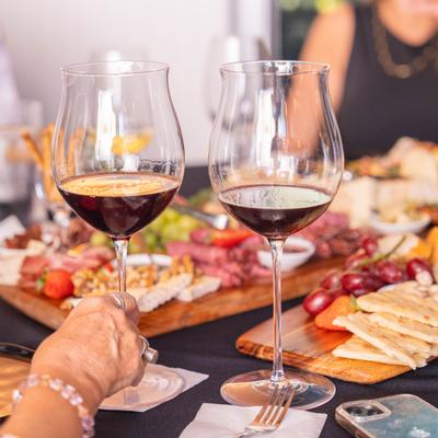 A group of guests sitting around a table enjoying wine and charcuterie food.