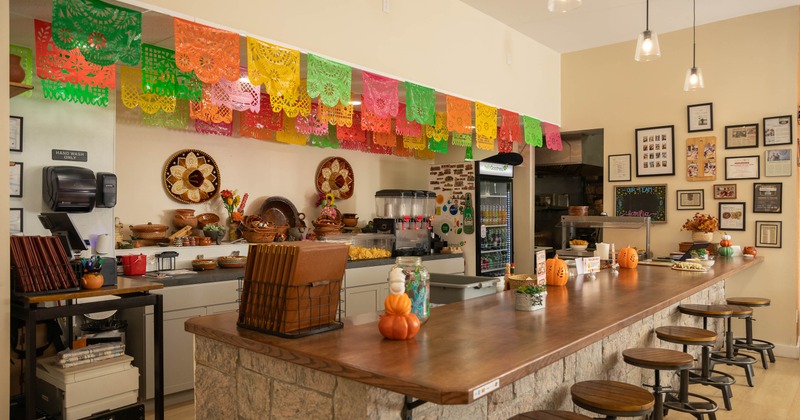 Interior - a stone service counter, papel picado banners, framed memorabilia, wooden bar stools