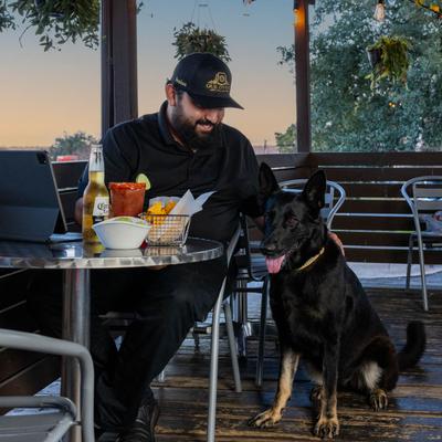 A person sitting at a table, petting a dog.