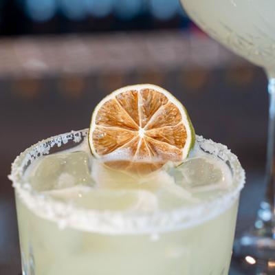 Margarita on the rocks garnished with a dehydrated lime wheel and a salt rim.