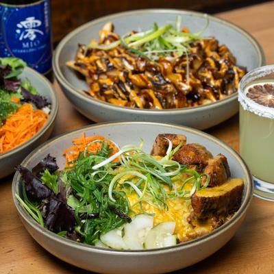 Assortment of Rice bowls with various toppings served alomgside a cocktail.