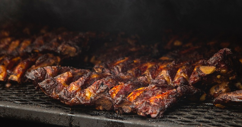 Ribs on a grill with smoke rising above them