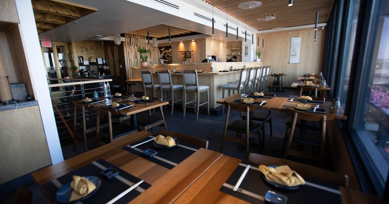 Interior, dining area, wooden top tables for four and two, bar with set up plates