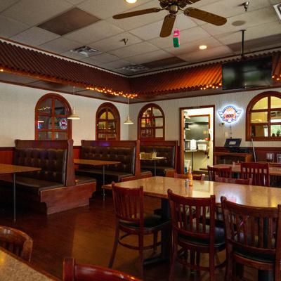 Dimly lit restaurant interior with wooden booths, tables, and glowing neon signs.