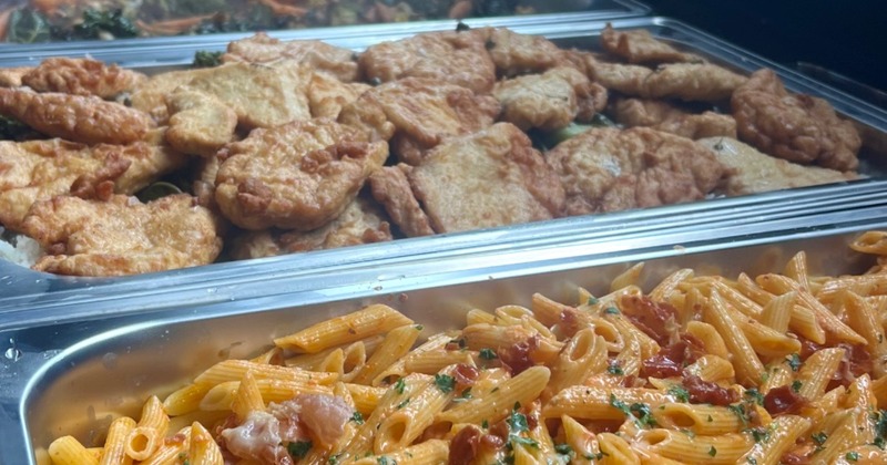 Buffet setup with several catering trays filled with food