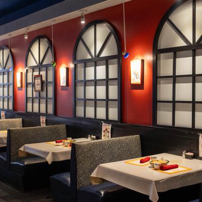 Booth tables beneath arched windows with wall lighting.