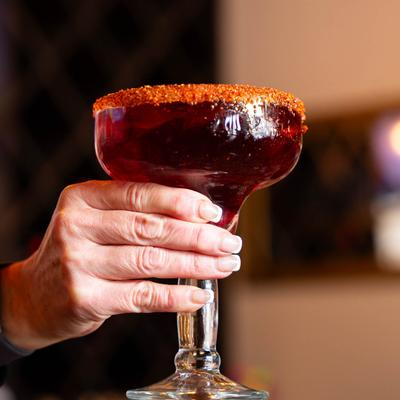 A hand holding a hibiscus margarita.