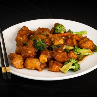 Fried chicken in sweet and spicy sauce on a plate with broccoli and baby corn.