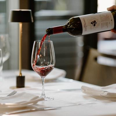 Red wine being poured into a glass on an elegantly set table.