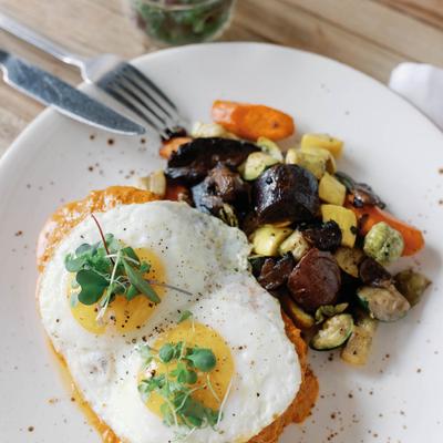 Dish with two fried eggs, cooked vegetables and mushrooms