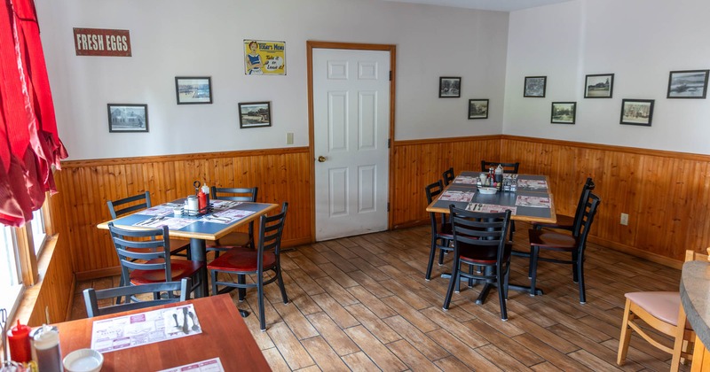 Interior, tables for four and six, ready for guests, various framed pictures, tile flooring