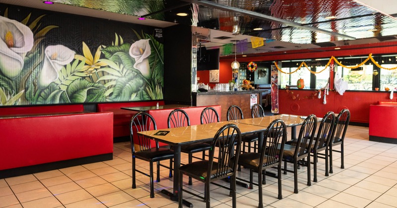 Restaurant interior with a mural of flowers, red booth seating, and decorated bar area