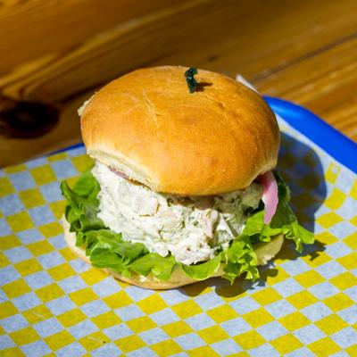 Chicken salad sandwich with lettuce and red onions on a bun.