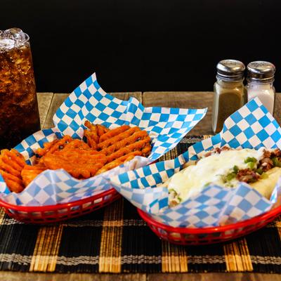 Philly sandwich with a side of waffle fries and a soft drink.