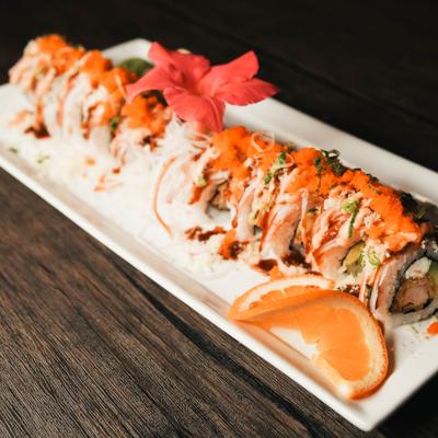 A sushi roll topped with orange fish roe and a creamy white sauce.