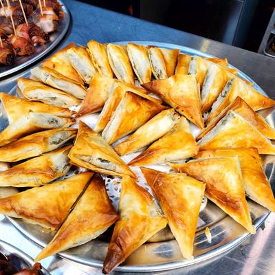 Large metal tray filled with golden-brown, crispy triangular pastries.