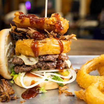 Western burgertopped with pulled pork and onion rings.
