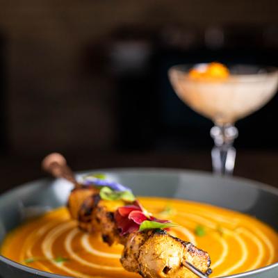 Saffron Butter Chicken, a cocktail in the background