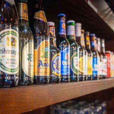 Lined up beer bottles on a bar shelf.