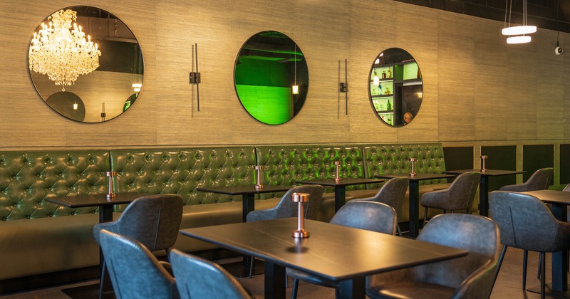 Interior, dining area, long banquette bench with tables, large round mirrors on the wall