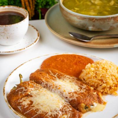 Chile Relleno topped with red tomato-based sauce and cheese, served with rice and beans.