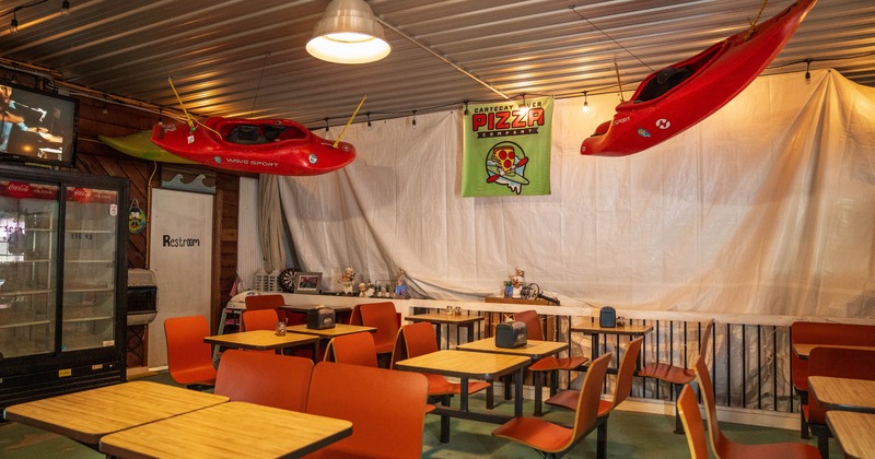 Inside, dining tables and chairs, kayaks hanging from the ceiling