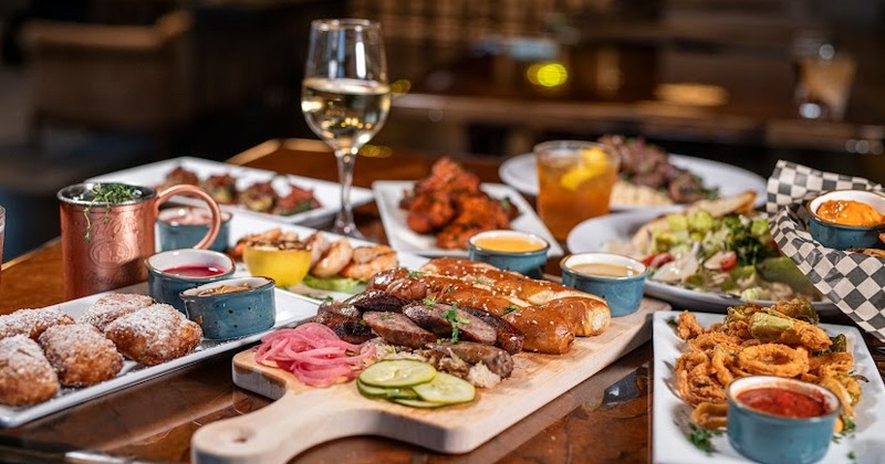 Various menu items served on the table with cocktails and a glass of wine