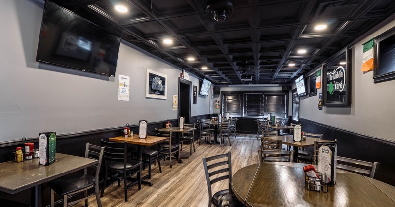 Interior, wooden tables, chairs, and multiple TVs showing broadcasts