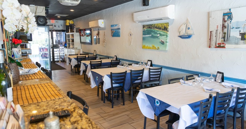 Interior of a cozy restaurant with black wooden chairs, white tablecloths