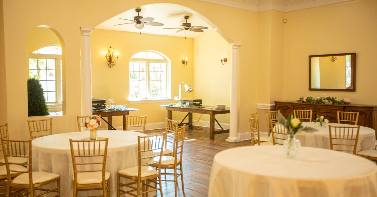 Interior, round tables with white tablecloths and wooden chairs with white leather seats