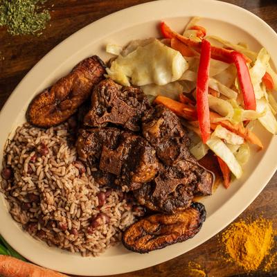 Oxtails Dinner with cabbage, plantains, and rice and peas.