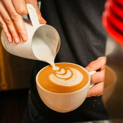 Hands preparing a lattee.